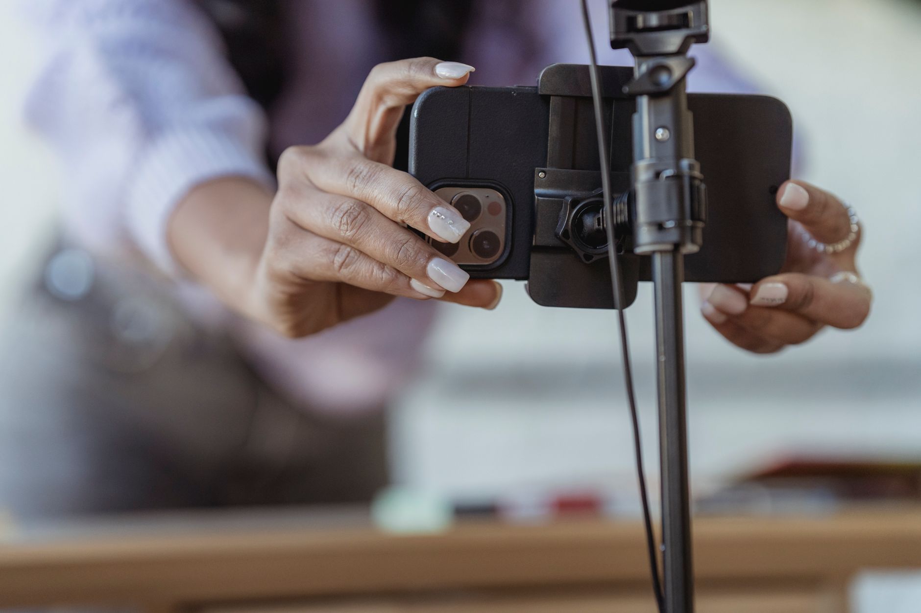 Close-up of hands fixing a smartphone into a tripod clamp, getting the camera lined up before recording.